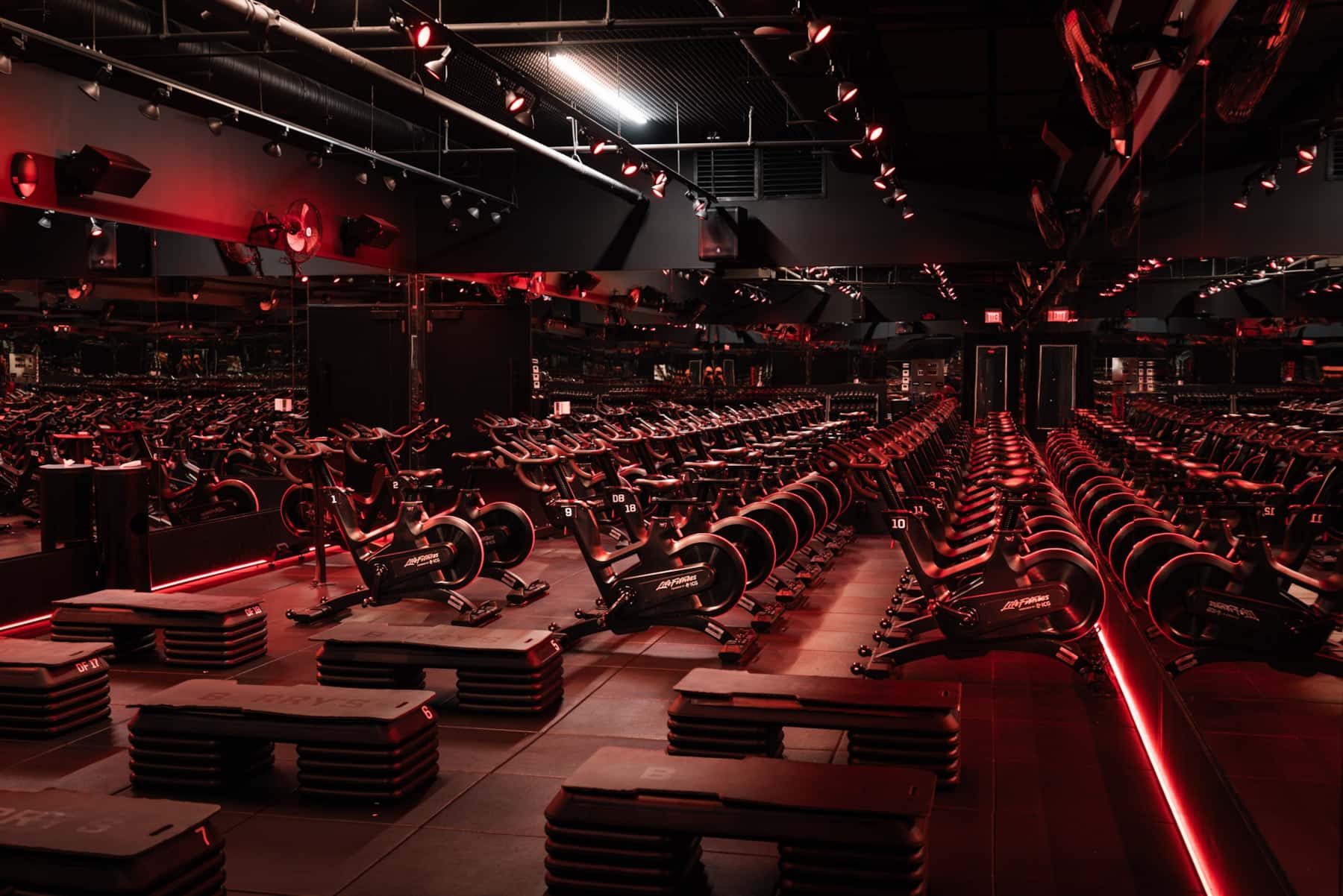 Estudio de indoor cycling de Barry’s con iluminación roja y bicicletas ICG